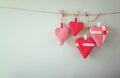 Christmas image of fabric red hearts hanging on rope in front of wooden background. retro filtered Royalty Free Stock Photo