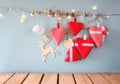 Christmas image of fabric red hearts and tree. wooden reindeer and garland lights, hanging on rope