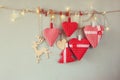 Christmas image of fabric red hearts and tree. wooden reindeer and garland lights, hanging on rope Royalty Free Stock Photo