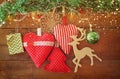 Christmas image of fabric red hearts and tree. wooden reindeer and garland lights, hanging on rope in front of wooden background Royalty Free Stock Photo