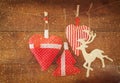 Christmas image of fabric red hearts and tree. wooden reindeer and garland lights, hanging on rope in front of wooden background. Royalty Free Stock Photo