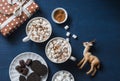 Christmas inspiration table - hot chocolate with marshmallows, cookies, gift box, christmas ornament reindeer on a blue background Royalty Free Stock Photo