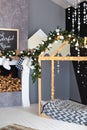 Christmas interior of a children`s bedroom with a wooden bed in shape of a house and a fireplace. New Year`s decor and a Christmas Royalty Free Stock Photo