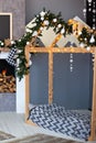 Christmas interior of children`s bedroom with wooden bed in shape of house. New Year decor and New Year fir-tree garland in a chil Royalty Free Stock Photo