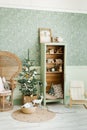 Christmas interior of the children`s room in mint colors. A Christmas tree in a wicker basket with toys, a cabinet with books and