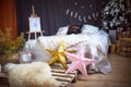 Christmas interior decor in loft style. A bed on a pallet, a large-knitted plaid, gold and pink stars, garlands, an easel. Royalty Free Stock Photo