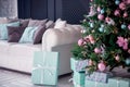 Christmas interior: decorated fir tree with blue, turquoise and pink balls, gift boxes and white sofa