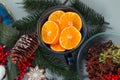 Christmas items on the table. Pieces of tangerines in a cup, fir twigs and cones, winter spices, decorations