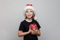 Christmas kid girl in Santa hat holding red gift box on white background, Xmas portrait Royalty Free Stock Photo