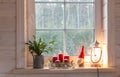 Christmas lantern, Angel, Christmas gnome, Christmas Cactus and red mug on the window of a wooden house overlooking the Royalty Free Stock Photo