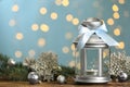 Christmas lantern with burning candle and festive ornaments on wooden table against blurred lights. Space for text Royalty Free Stock Photo