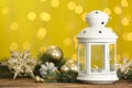 Christmas lantern with burning candle and festive ornaments on wooden table against blurred lights. Space for text Royalty Free Stock Photo