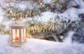 Christmas lantern with burning candle shines on snow and spruce branches, snowfall winter scene with light and bokeh Royalty Free Stock Photo