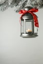 Christmas lantern with candle hanging on snowy fir tree branch against light background. Space for text Royalty Free Stock Photo