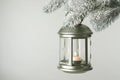 Christmas lantern with candle hanging on snowy fir tree branch against light background. Space for text Royalty Free Stock Photo