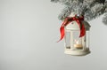 Christmas lantern with candle hanging on snowy fir tree branch against light background. Space for text Royalty Free Stock Photo