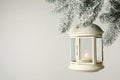 Christmas lantern with candle hanging on snowy fir tree branch against light background. Space for text Royalty Free Stock Photo