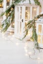 Christmas lanterns and snowy fir branches over white wooden background with lights.  New Year`s decoration with a fir tree in Royalty Free Stock Photo