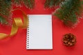 Christmas layout. Spruce branch, pine cone, Notepad and gold ribbon on a red background Royalty Free Stock Photo