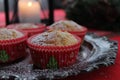 Christmas lemon vanilla muffins in red Christmas cases  placed on a rustic metal plate  candle and green branches in background. Royalty Free Stock Photo