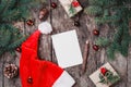 Christmas letter on wooden background with red Santa hat, Fir branches, pine cones, red decorations Royalty Free Stock Photo