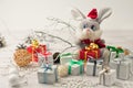 Christmas light gray background on whitewashed wooden boards with a toy hare in a Santa Claus costume with gifts Royalty Free Stock Photo