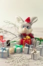 Christmas light gray background on whitewashed wooden boards with a toy hare in a Santa Claus costume with gifts Royalty Free Stock Photo