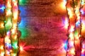 Christmas lights or colorful garland on the sides on wooden background. Bright and colorful New Year festive decorations Royalty Free Stock Photo