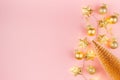 Christmas lights and decoration - golden stars garland glowing on soft light pastel pink background with christmas tree, balls. Royalty Free Stock Photo