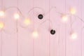 Christmas lights garland with black and white balls border over pink background. Flat lay, copy space Royalty Free Stock Photo