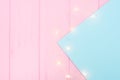 Christmas lights garland on blue paper border over pink wooden background. Scandinavian flat lay, copy space Royalty Free Stock Photo