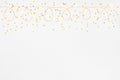 Christmas lights garland border and golden stars confetti over white background. Flat lay, copy space Royalty Free Stock Photo