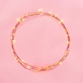 Christmas lights garland circular border over pink background. Flat lay, copy space. Royalty Free Stock Photo