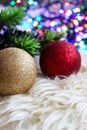 Christmas lights and red and gold christmas tree decorations on a white fur carpet. Glitter and sparkle during the holidays.