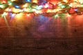 Christmas lights on wooden background. New Year festive decorations with colorful glowing Christmas lights. Colorful Royalty Free Stock Photo
