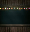 Christmas lights on wooden blackboard Royalty Free Stock Photo