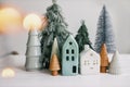 Christmas little houses and trees with golden lights bokeh on white background. Festive modern decor. Happy holidays. Miniature Royalty Free Stock Photo