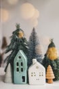 Christmas little houses and trees with golden lights bokeh on white background. Festive modern decor. Happy holidays. Miniature Royalty Free Stock Photo