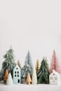 Christmas little houses and trees on white background. Festive modern decor. Happy holidays. Miniature cozy village, ceramic