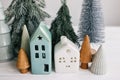 Christmas little houses and trees on white background. Holiday festive decor. Miniature village, ceramic houses, wooden christmas