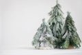 Christmas little snowy trees on white background. Miniature handmade pine trees with snowy branches. Festive modern decor, zero