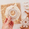 Christmas macrame toys in child hand. White background. Natural materials - cotton thread, wood beads and stick. Eco decorations, Royalty Free Stock Photo