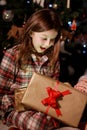 Christmas magic. Adorable excited child girl opening shining Christmas gift box, sitting near Xmas tree, celebrating Royalty Free Stock Photo