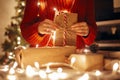 christmas magic moments. hands holding christmas present in lights in evening festive room under tree in illumination. space for Royalty Free Stock Photo