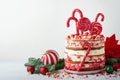 Christmas many layers cake decorated with lolli pops, red and white confetti on white cake stand, Christmas balls, fir branches on