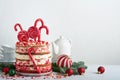 Christmas many layers cake decorated with lolli pops, red and white confetti on white cake stand, Christmas balls, fir branches on