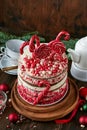 Christmas many layers cake decorated with lolli pops, red and white confetti on white cake stand, Christmas balls, fir branches on