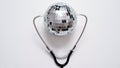 Christmas medical banner.Close-up of stethoscope and disco ball on white background,top view,flat lay,copy space.New Year or