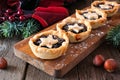 Christmas mincemeat tarts on a serving board. Table scene on rustic wood.