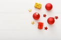Christmas minimalist composition witn copy space made of gifts, red bauble decorations, gold and red stars on white wooden table Royalty Free Stock Photo